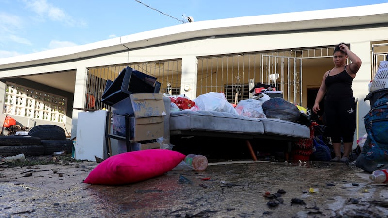 A woman looks at her water-damaged belongings after flooding caused by Hurricane Fiona tore...