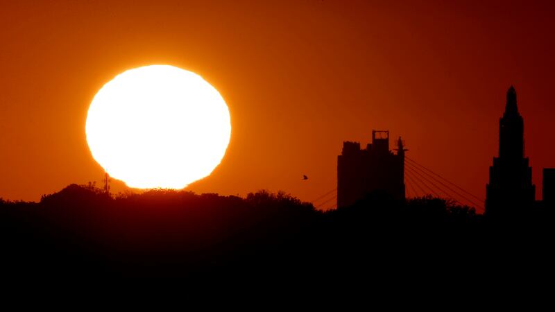 FILE - The sun sets beyond the downtown skyline of Kansas City, Mo., as the autumnal equinox...